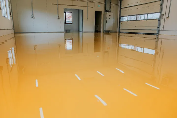 Industrial epoxy floor in a warehouse with yellow safety line striping