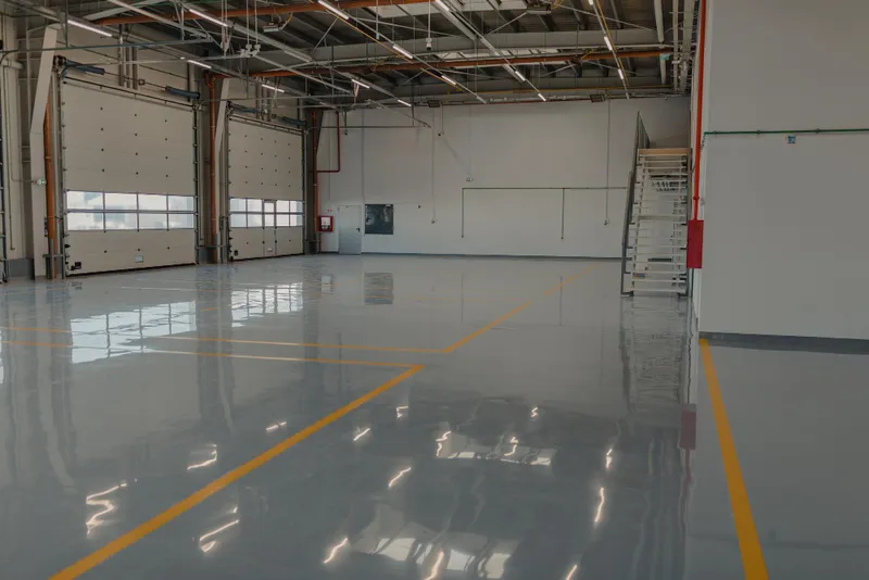 Piso epóxico industrial en almacén con marcas de seguridad amarillas
