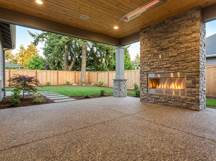 Covered outdoor patio with stone fireplace and coated concrete floor in Central NJ