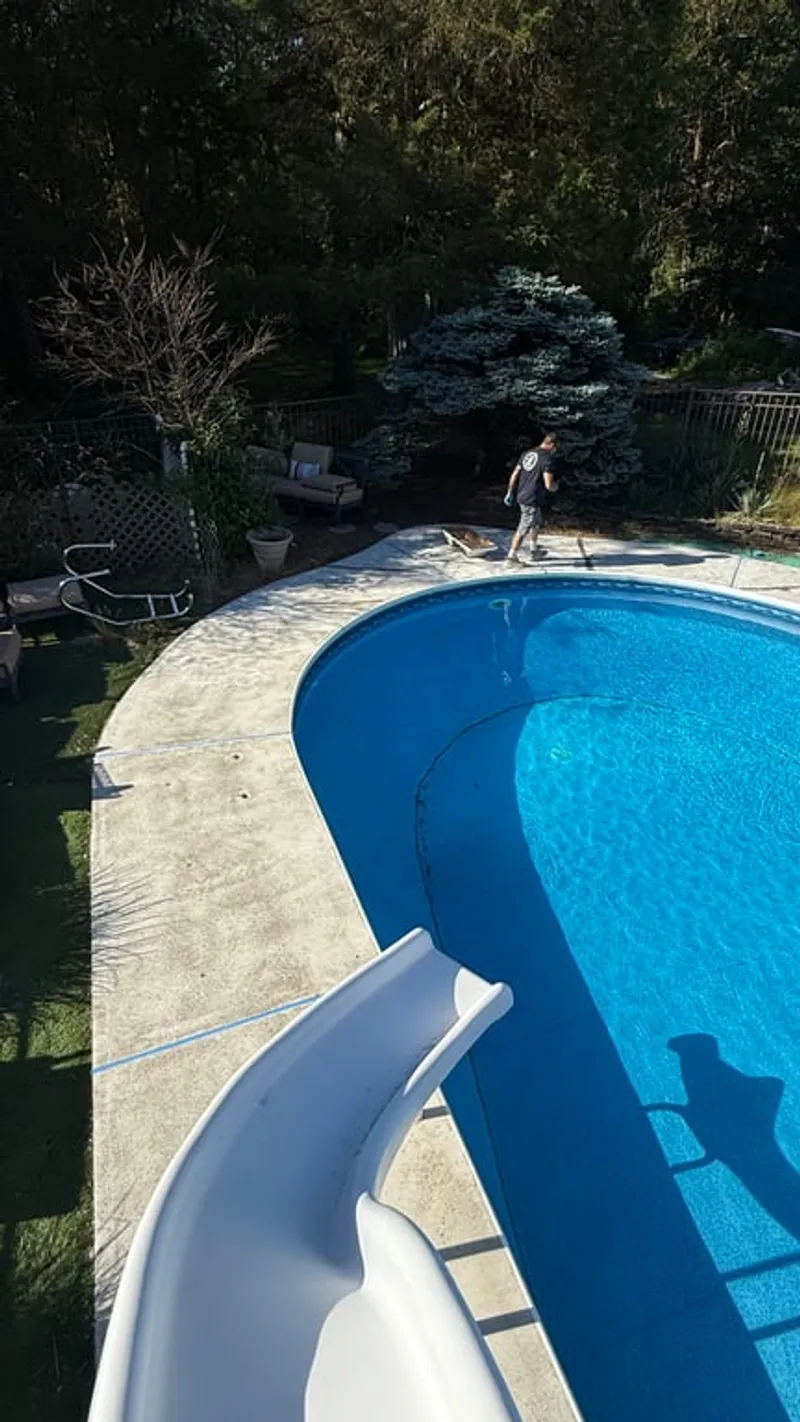 Aerial view of ground-level pool deck with water slide after concrete grinding preparation in Hillsborough Township, NJ before Simiron Stonewash flake coating installation
